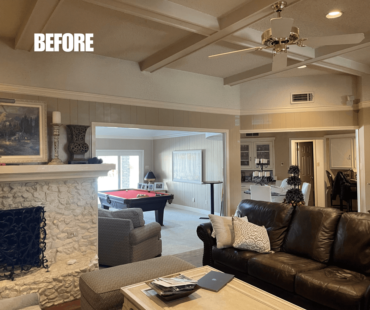 BEFORE: Living room with a ceiling fan, stone fireplace, and various furniture. A pool table is visible in an adjacent room.