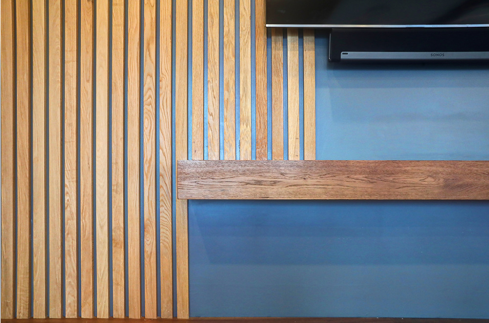 The wood slats are vertical, with varied spacing, creating a textured look against a blue-painted wall.